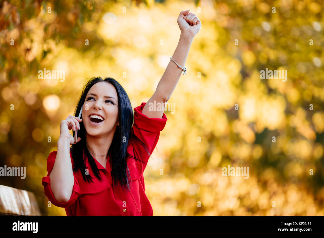 Heureux happy young woman listening de très bonnes nouvelles sur smartphone et être très heureux à l'automne la nature. Banque D'Images