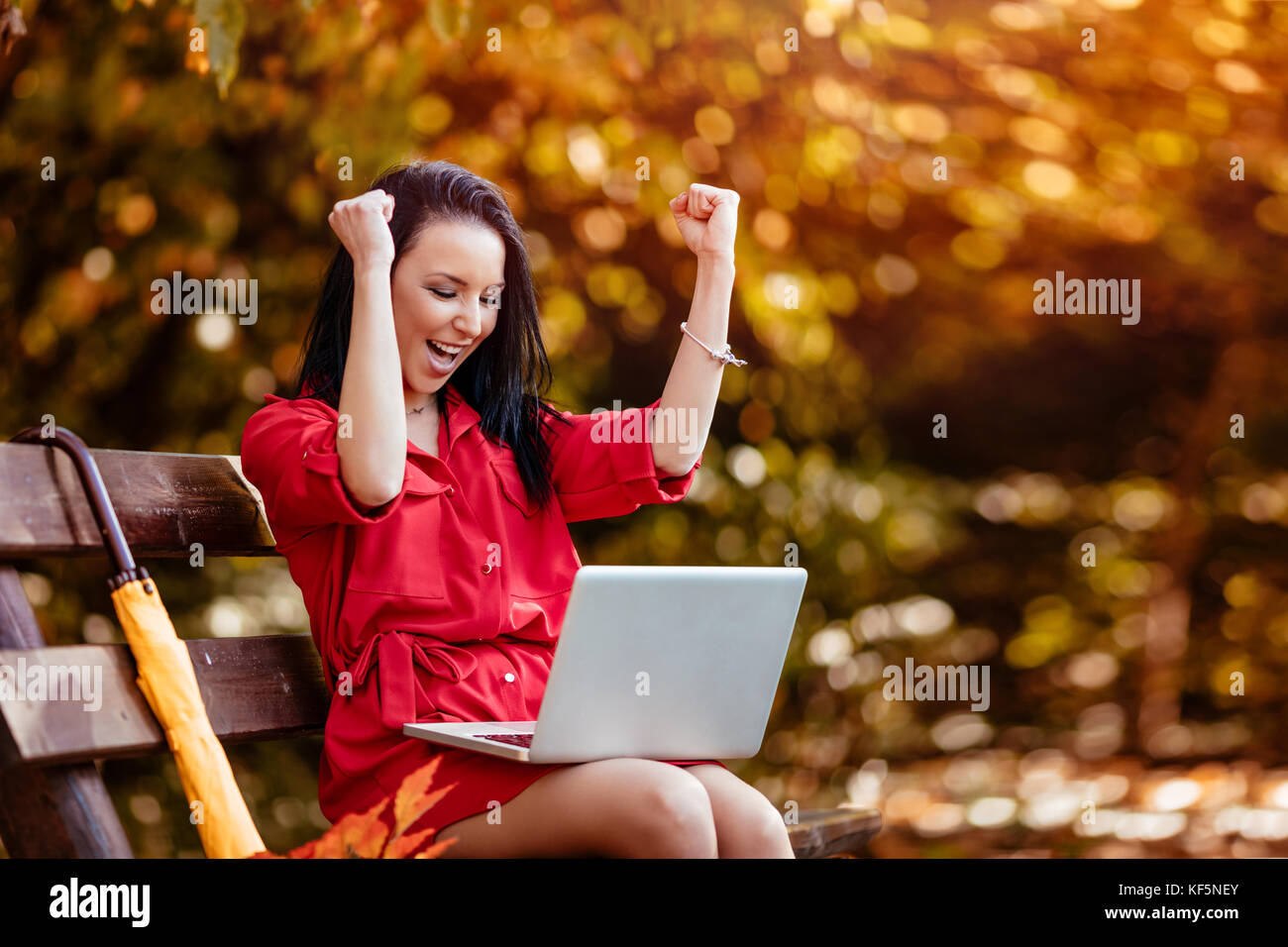 Jeune femme entrepreneur euphorique célébrant la réussite de l'entreprise lecture bonnes nouvelles sur l'ordinateur portable dans le parc. Banque D'Images