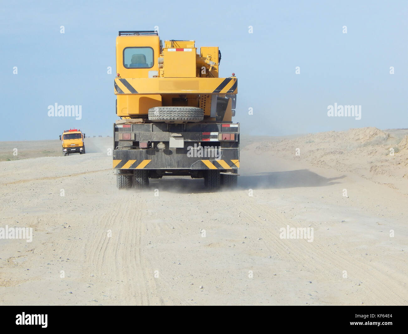 Grue mobile voyage le long d'une route de terre poussiéreuse. Banque D'Images