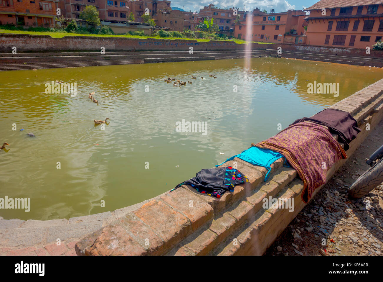 BHAKTAPUR, NÉPAL - 04 NOVEMBRE 2017 : gros plan de la scène urbaine traditionnelle avec un étang artificiel avec des canards nageant et des vêtements secs au soleil à Bhaktapur ville, Népal Banque D'Images BHAKTAPUR, NÉPAL - 04 NOVEMBRE 2017 : gros plan de la scène urbaine traditionnelle avec un étang artificiel avec des canards nageant et des vêtements secs au soleil à Bhaktapur ville, Népal Banque D'Images