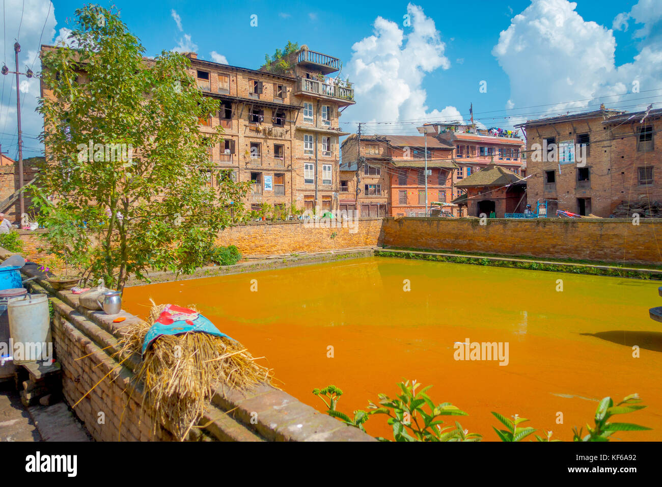 BHAKTAPUR, NÉPAL - 04 NOVEMBRE 2017 : gros plan de la scène urbaine traditionnelle avec un étang artificiel d'eau jaune dans la ville de Bhaktapur, Népal Banque D'Images BHAKTAPUR, NÉPAL - 04 NOVEMBRE 2017 : gros plan de la scène urbaine traditionnelle avec un étang artificiel d'eau jaune dans la ville de Bhaktapur, Népal Banque D'Images