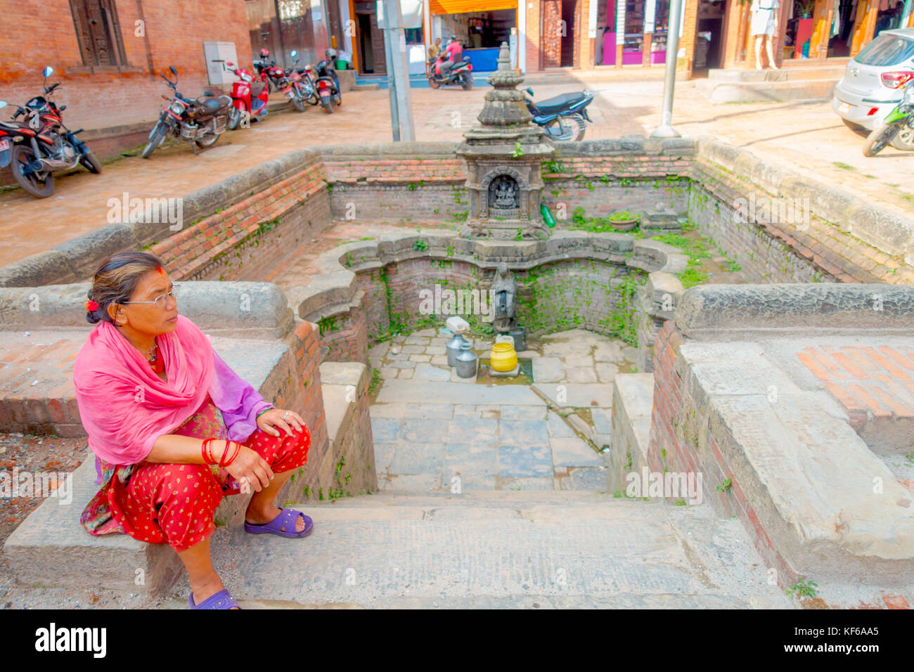 BHAKTAPUR, NÉPAL - 04 NOVEMBRE 2017 : femme non identifiée assise dans une place près d'une fontaine vide vue de l'ancien temple hindou dans la place Durbar à Bhaktapur, c'est la ville avec plus de temples pour la région Banque D'Images BHAKTAPUR, NÉPAL - 04 NOVEMBRE 2017 : femme non identifiée assise dans une place près d'une fontaine vide vue de l'ancien temple hindou dans la place Durbar à Bhaktapur, c'est la ville avec plus de temples pour la région Banque D'Images