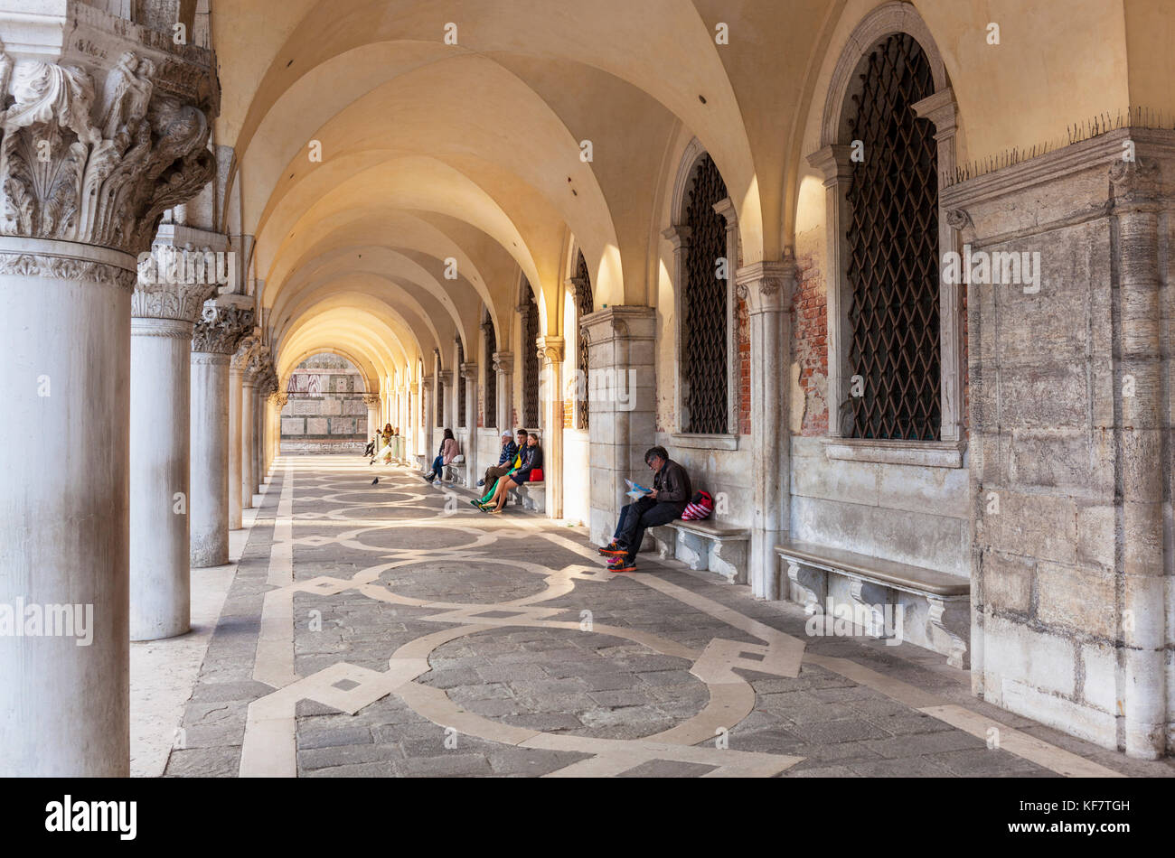 Venise ITALIE VENISE Les gens assis sous les arches dans l'arche portique du Palais des Doges (Palazzo Ducale) Place Saint Marc Venise Italie Europe de l'UE Banque D'Images
