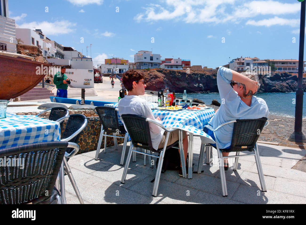 Les gens se détendre sur la terrasse d'un café/restaurant avec vue sur le vieux port de Cotillo, Fuerteventura, Espagne Banque D'Images