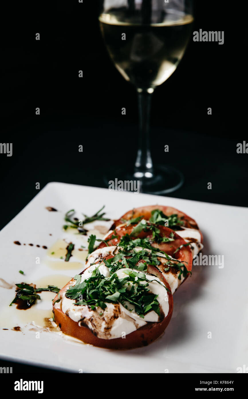 Salade caprese italien frais de fromage mozzarella, tomates et basilic sur une assiette blanche et fond noir Banque D'Images