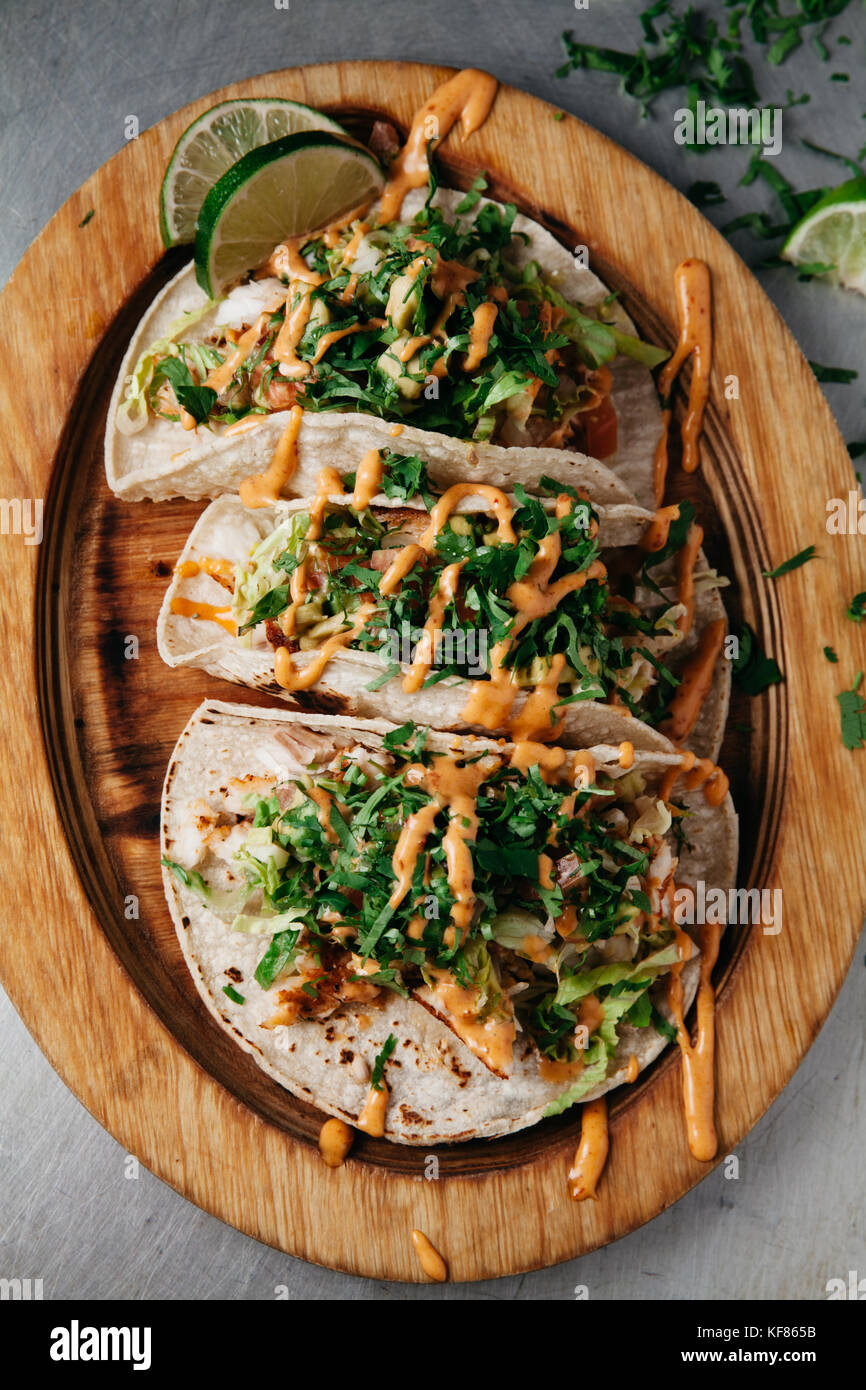 Tacos au poisson frais avec laitue, tomate, oignon, AVOCAT, garni de tranches de lime et beaucoup de coriandre Banque D'Images