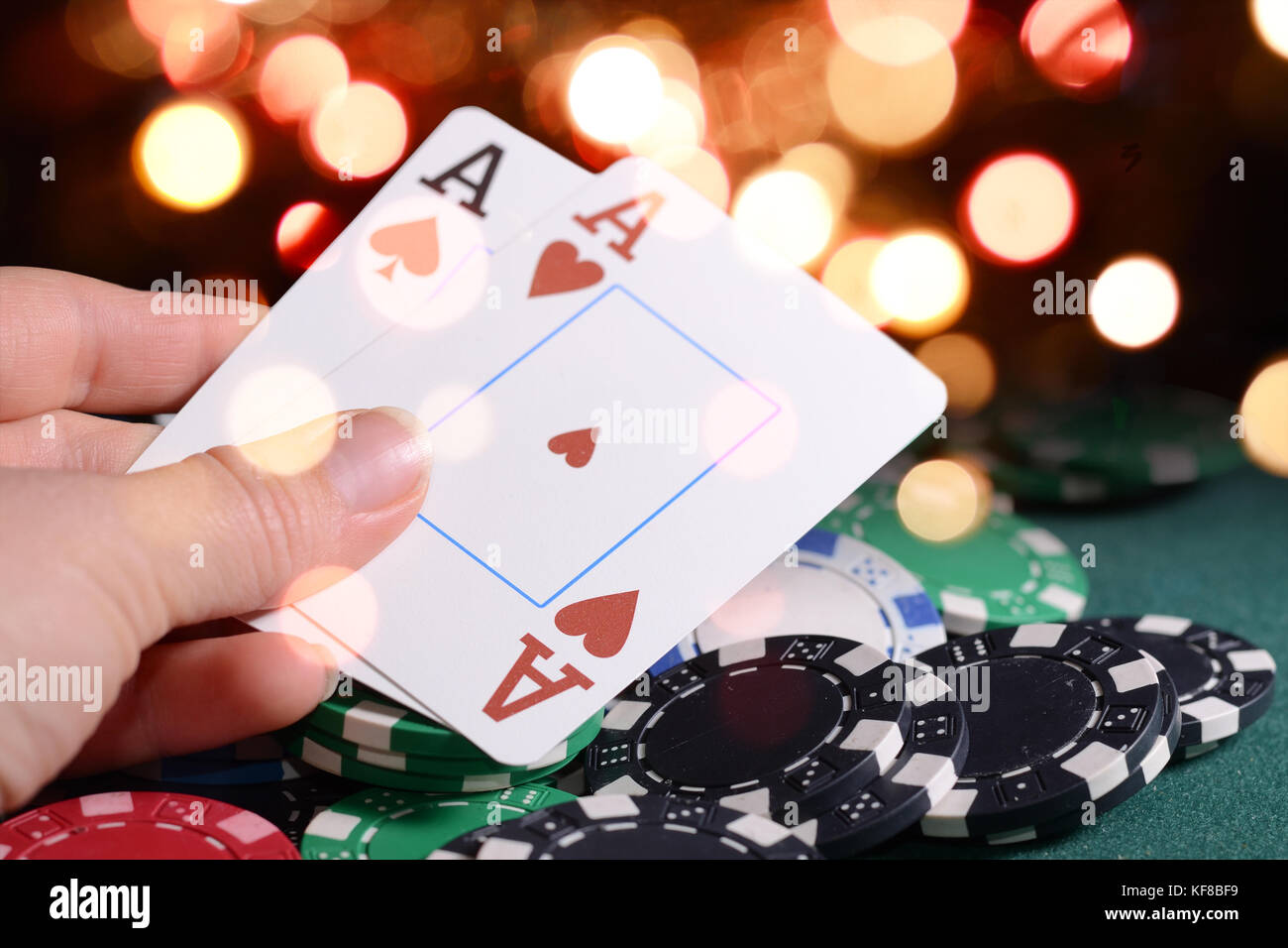 Jetons de Casino et paire d'as en main du croupier un bokeh lumineux contre feux. Thème du jeu le concept. Banque D'Images