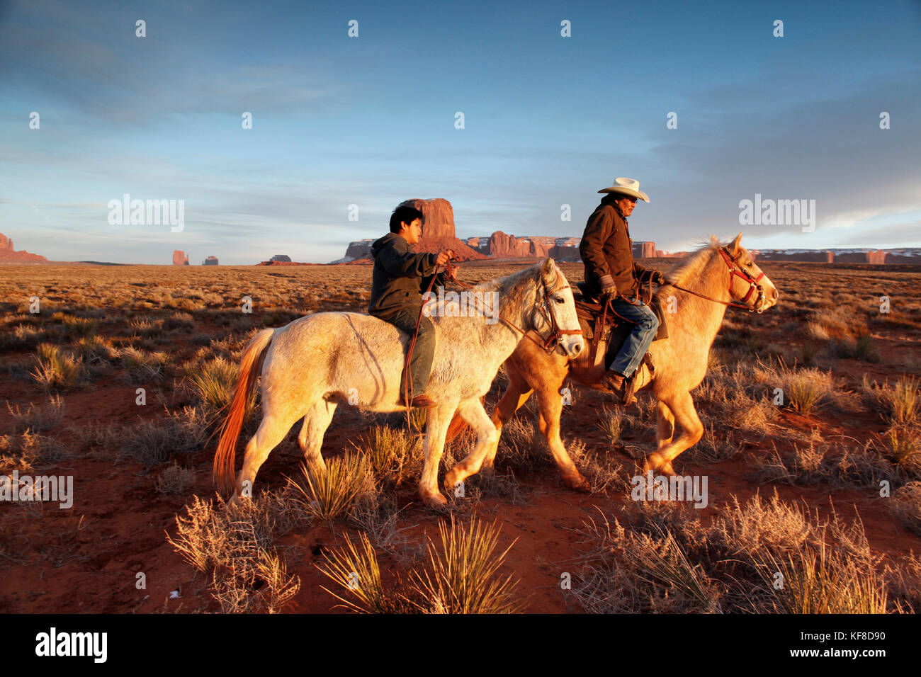 Usa ; Arizona ;, Monument Valley Navajo Tribal Park, un homme navajo et son fils monter à cheval avec Mitchell butte et mitchell mesa dans la distance Banque D'Images