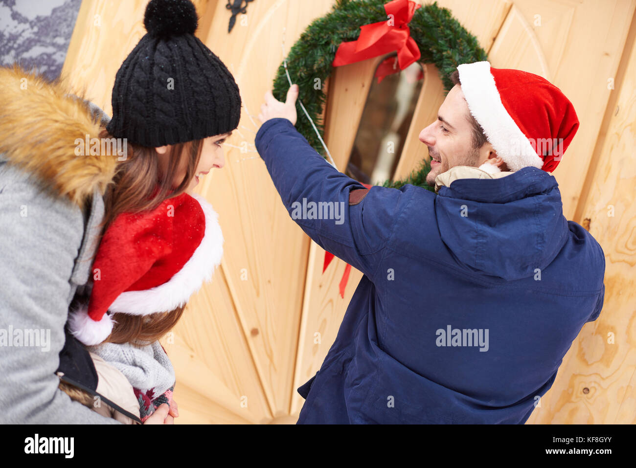 L'homme accroché la couronne de Noël sur la porte Banque D'Images