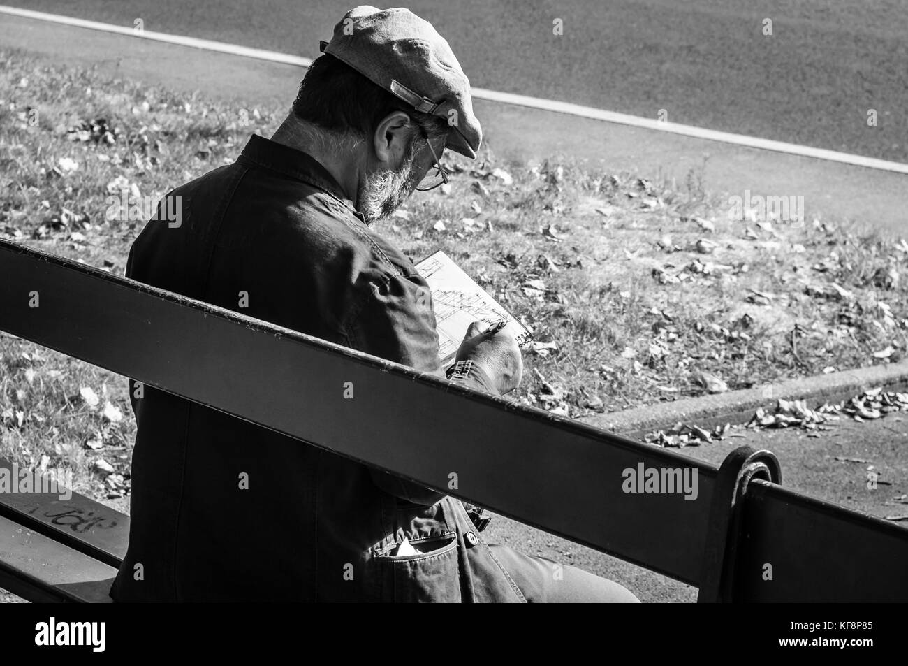 Artiste Français de sexe masculin, le port d'un chapeau plat, croquis, alors qu'il était assis sur un banc, à Versailles, France. Noir et blanc. Banque D'Images