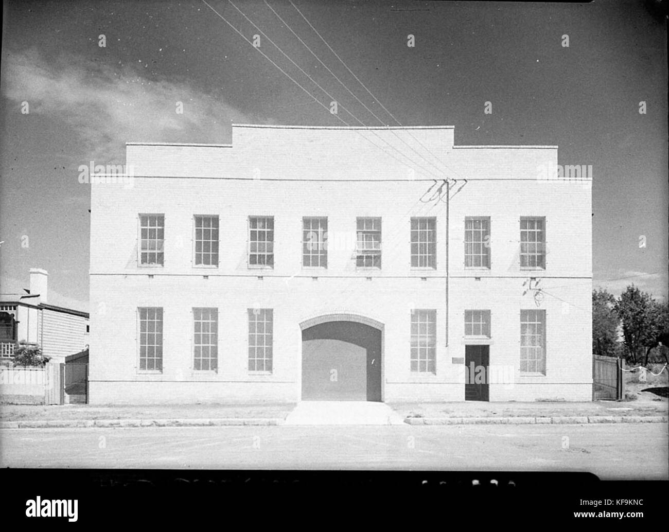 L'image montre la façade avant d'un bâtiment d'usine non identifié. Le style architectural suggère une structure industrielle de la fin du XIXe ou du début du XXe siècle, avec de grandes fenêtres et des briques. Banque D'Images
