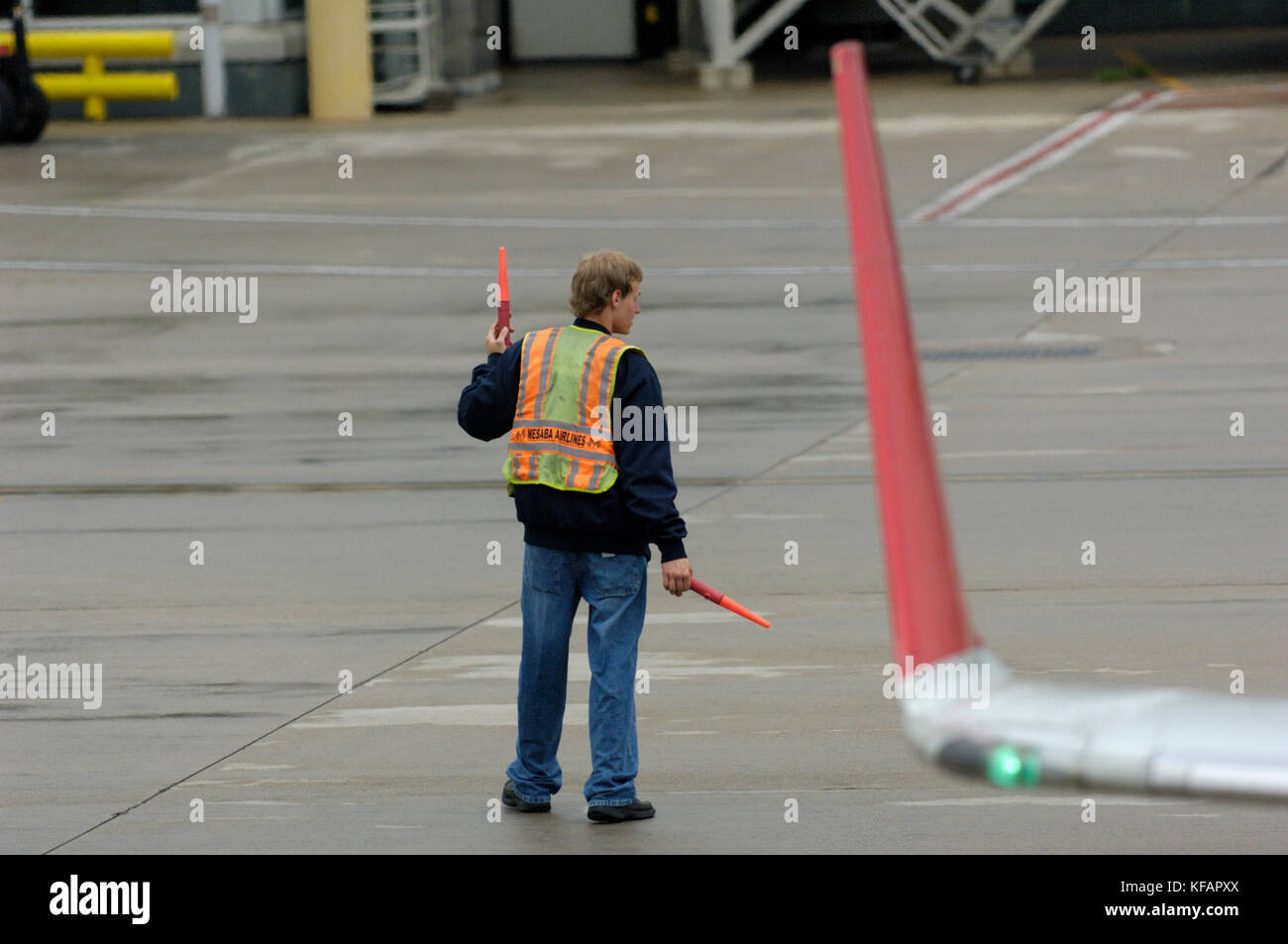 Le port d'un placier hi-viz tabard orange avec des matraques et le winglet de Northwest Airlink - Pinnacle Airlines Bombardier CRJ-440 poussant en arrière à partir de Banque D'Images