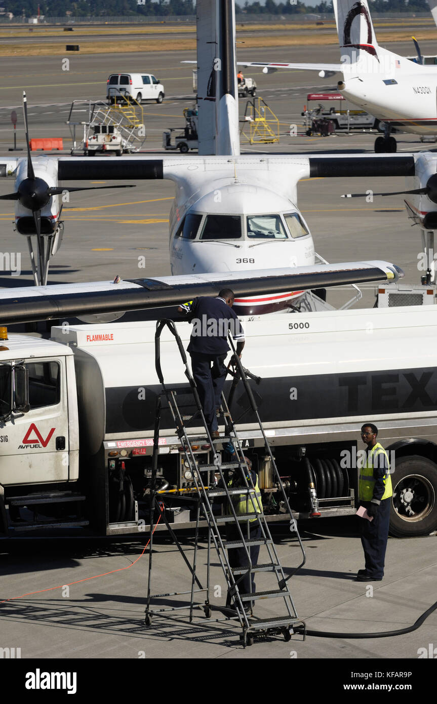 Les ravitailleurs et chariot avec un Horizon Air Bombardier DHC-8 Dash 8-200 garé et queue-fin d'un DHC-8 derrière Q400 Dash 8-400 Banque D'Images