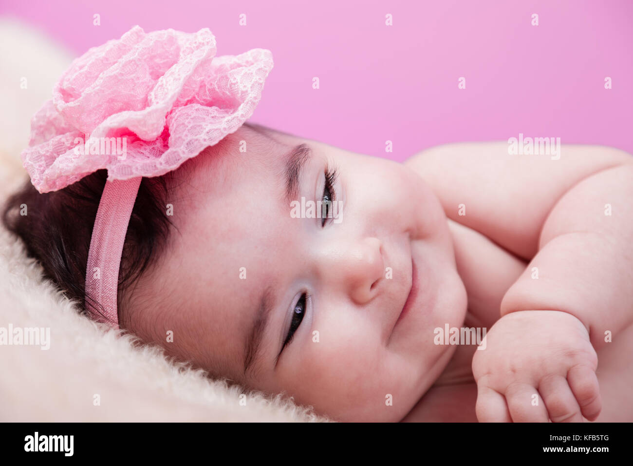 Mignon, joli, heureux, chubby portrait de fille de bébé avec un grand sourire de naughty. Nu ou nu sur une couverture moelleuse. Serre-tête à fleurs roses. Quatre mois bébé fille Banque D'Images