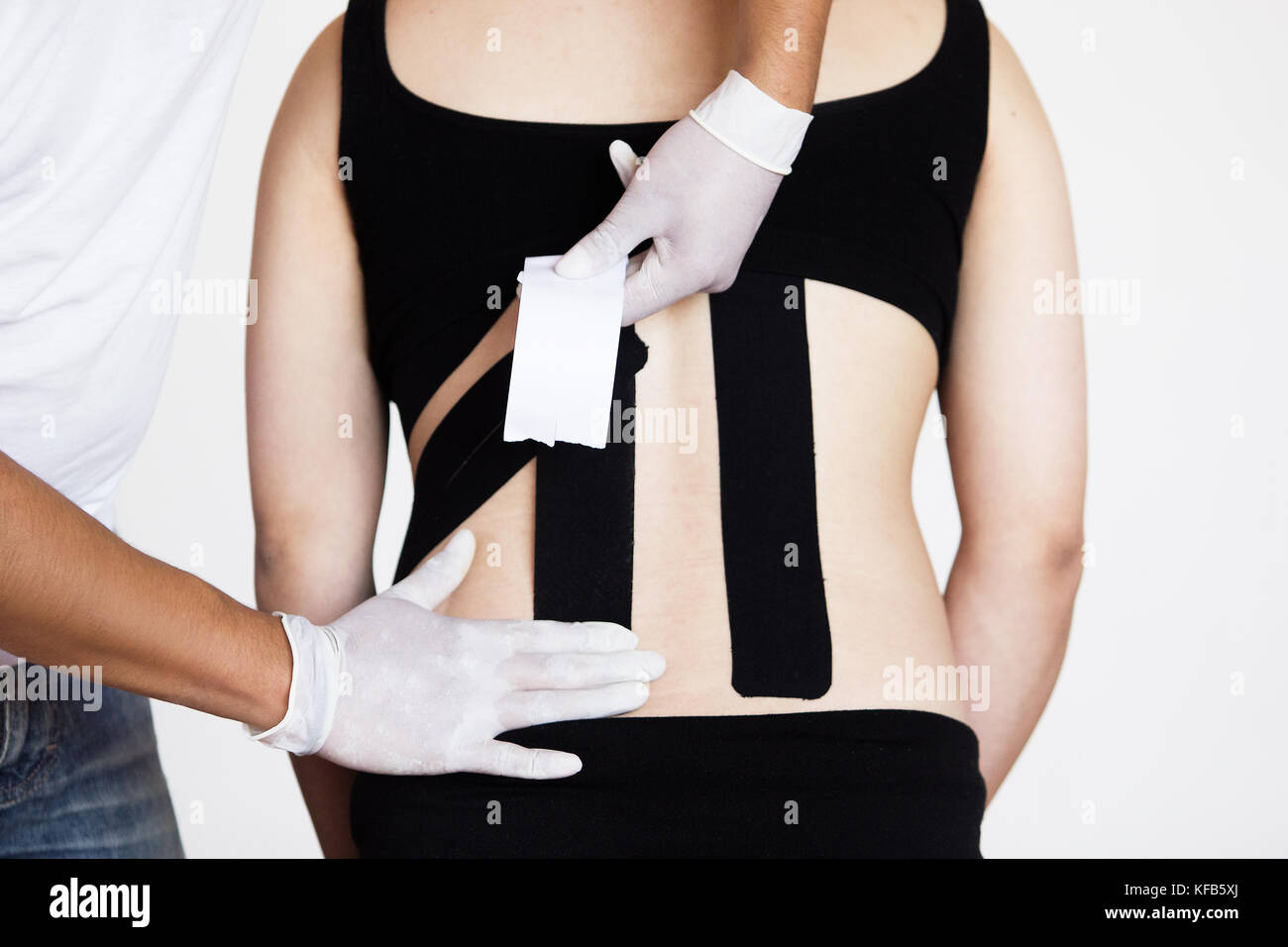 Un médecin physiothérapeute avec des gants l'application kinesio taping sur le dos d'une femme enceinte à réduire les maux de dos Banque D'Images