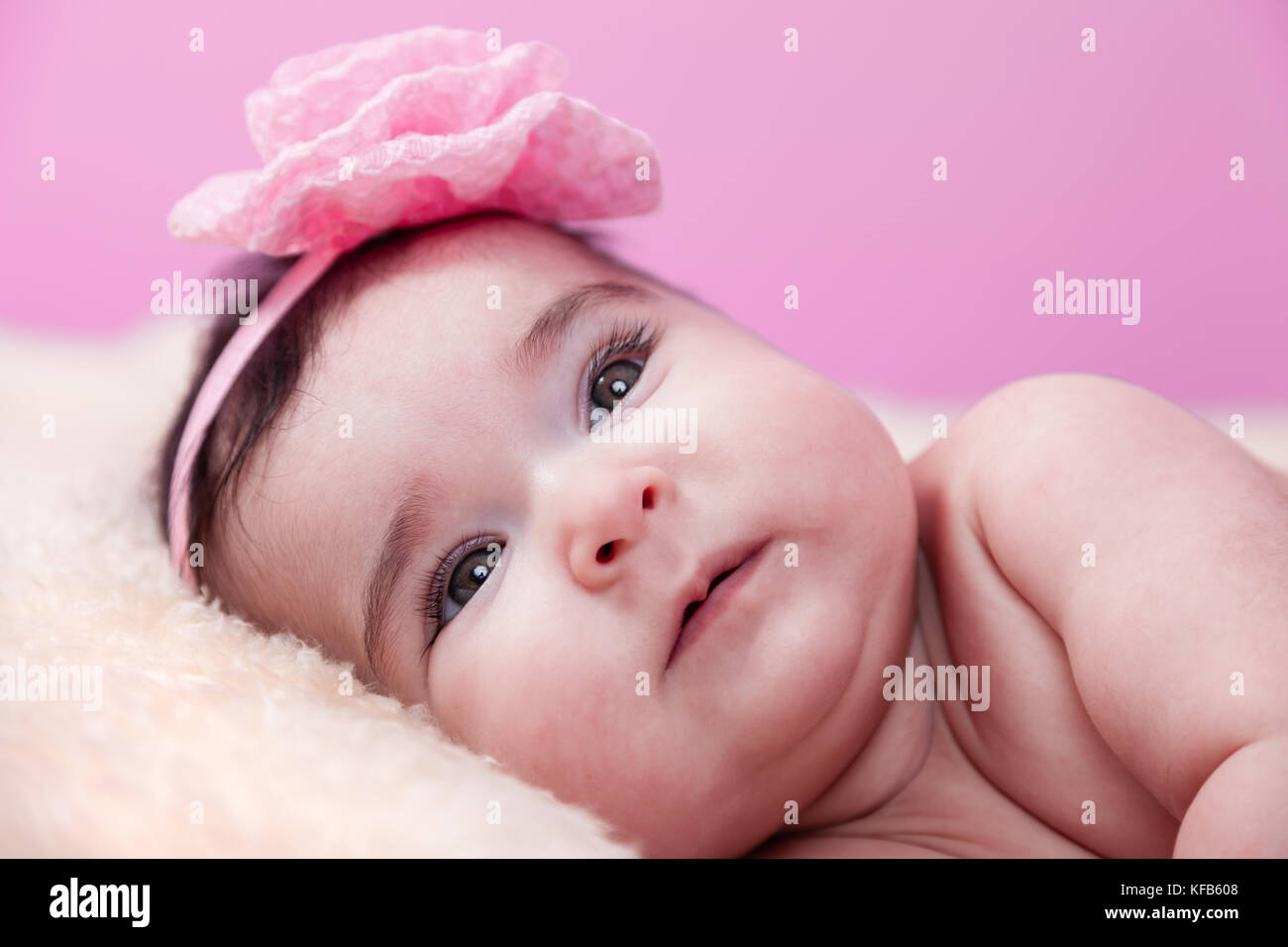 Mignon, joli, heureux, chubby portrait de fille de bébé souriant. Couché nu ou nu sur une couverture moelleuse. Serre-tête à fleurs roses. Quatre mois Banque D'Images