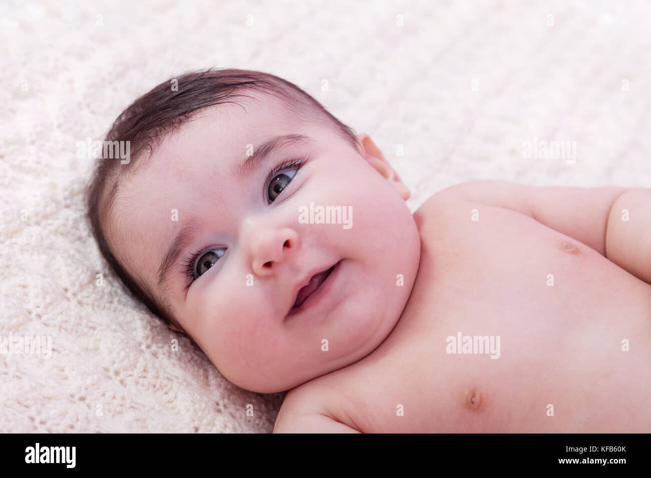 Portrait de petite fille mignon, joli, heureux, souriant. Couché nu ou nu sur une couverture moelleuse. Quatre mois Banque D'Images