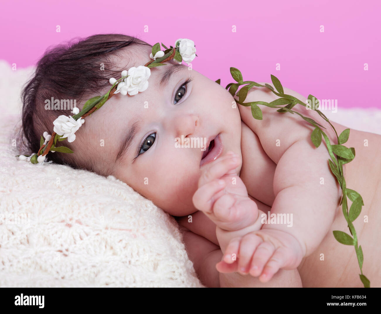 Mignon, joli, heureux, chubby portrait de fille de bébé, nu ou nu, sur une couverture moelleuse portant un bandeau de couronne ou de headaddress floral. Recherche. Quatre lun Banque D'Images