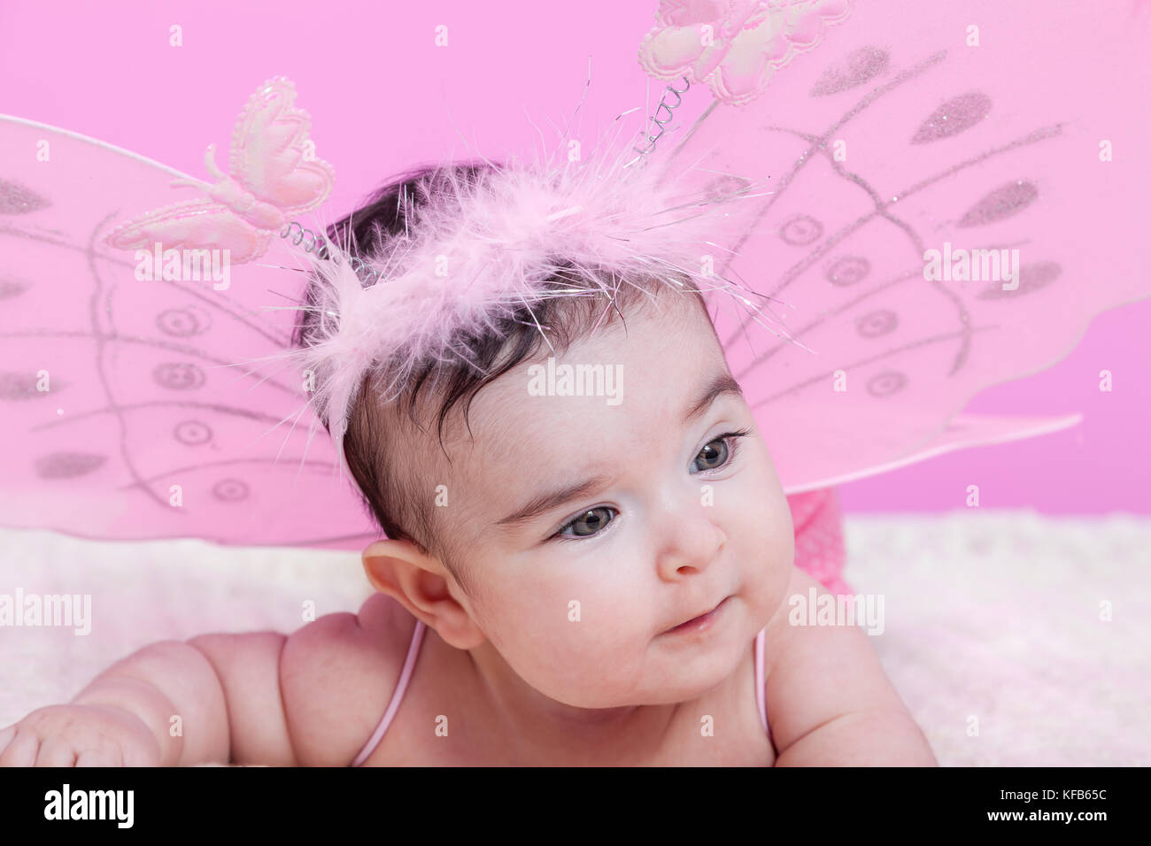 Mignon, joli, heureuse, chubby et smiling baby girl portrait, avec les ailes de papillon rose et serre-tête avec des antennes comme les papillons. 4 mois Banque D'Images