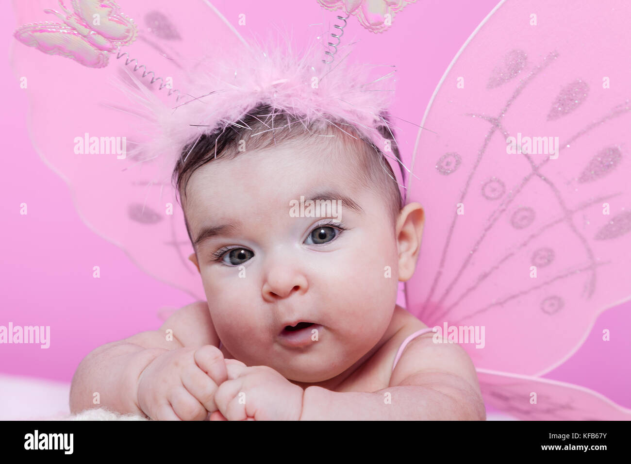 Mignon, joli, heureuse, chubby et smiling baby girl portrait, avec les ailes de papillon rose et serre-tête avec des antennes comme les papillons. 4 mois Banque D'Images
