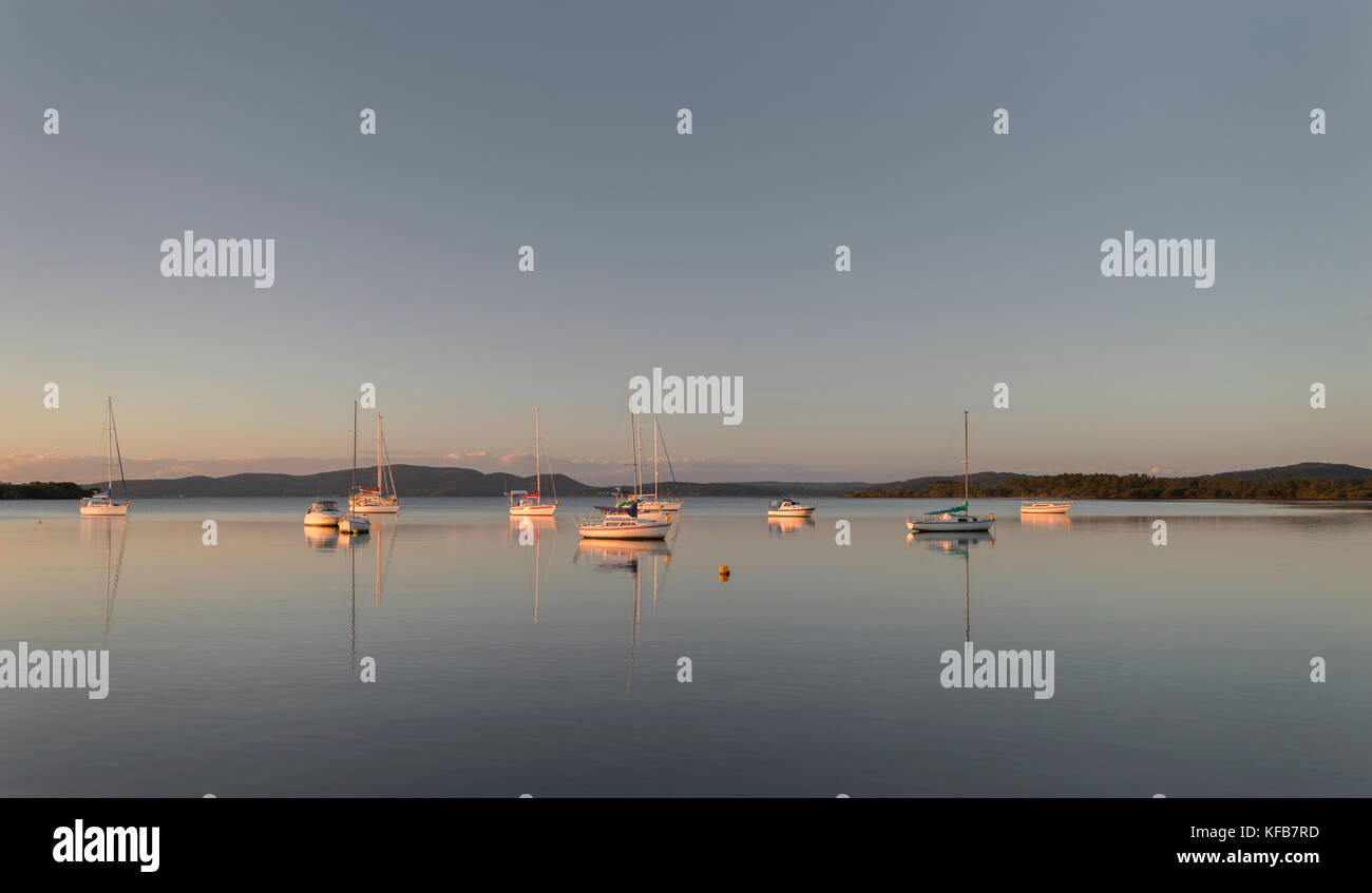 Scène magnifiquement lite de yachts et bateaux avec des réflexions dans la baie de Port Stephens, New South Wales, Australie. Banque D'Images