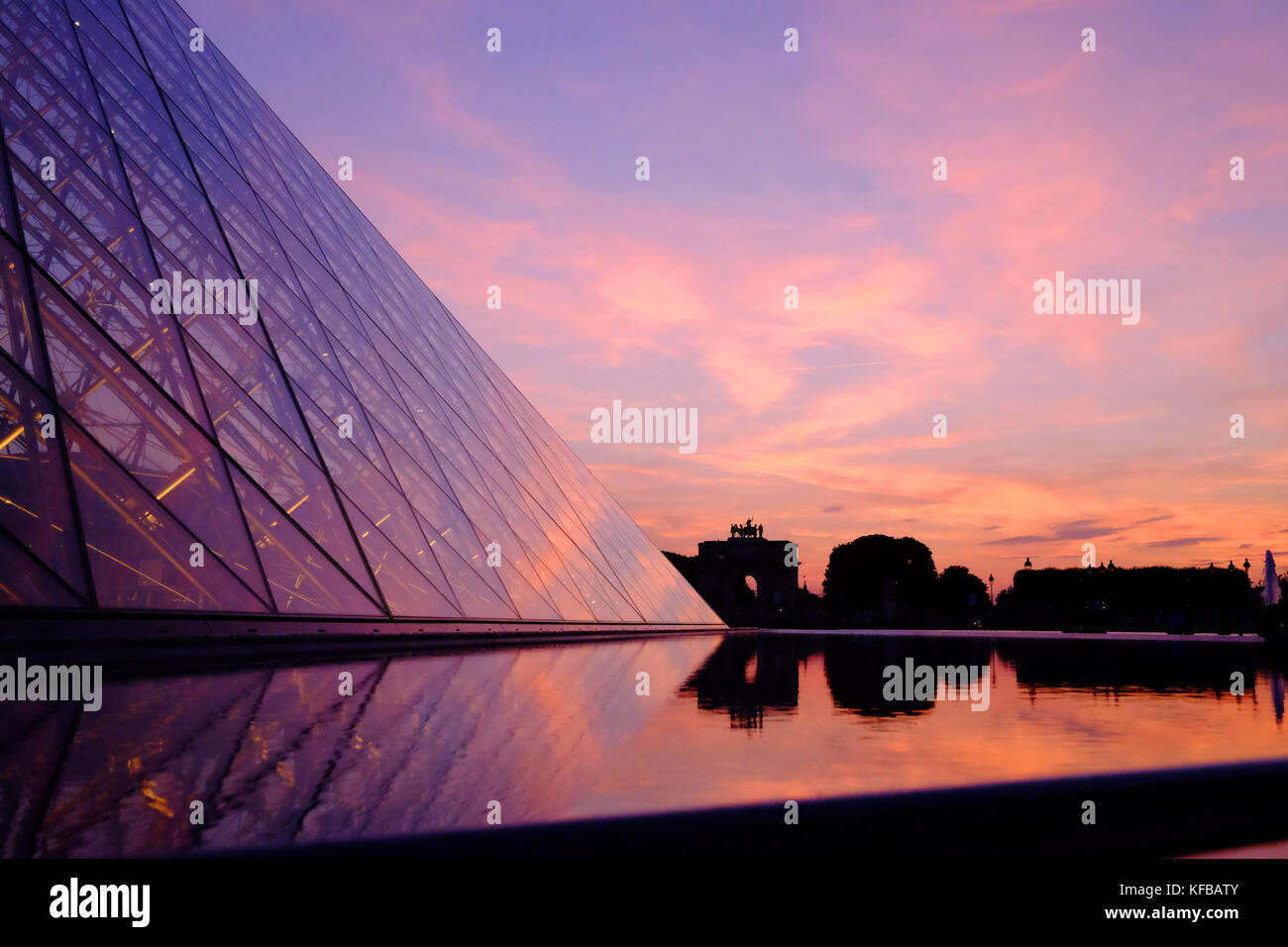 La pyramide du Louvre à Paris, France au coucher du soleil un soir d'été et les réflexions dans la fontaine Banque D'Images
