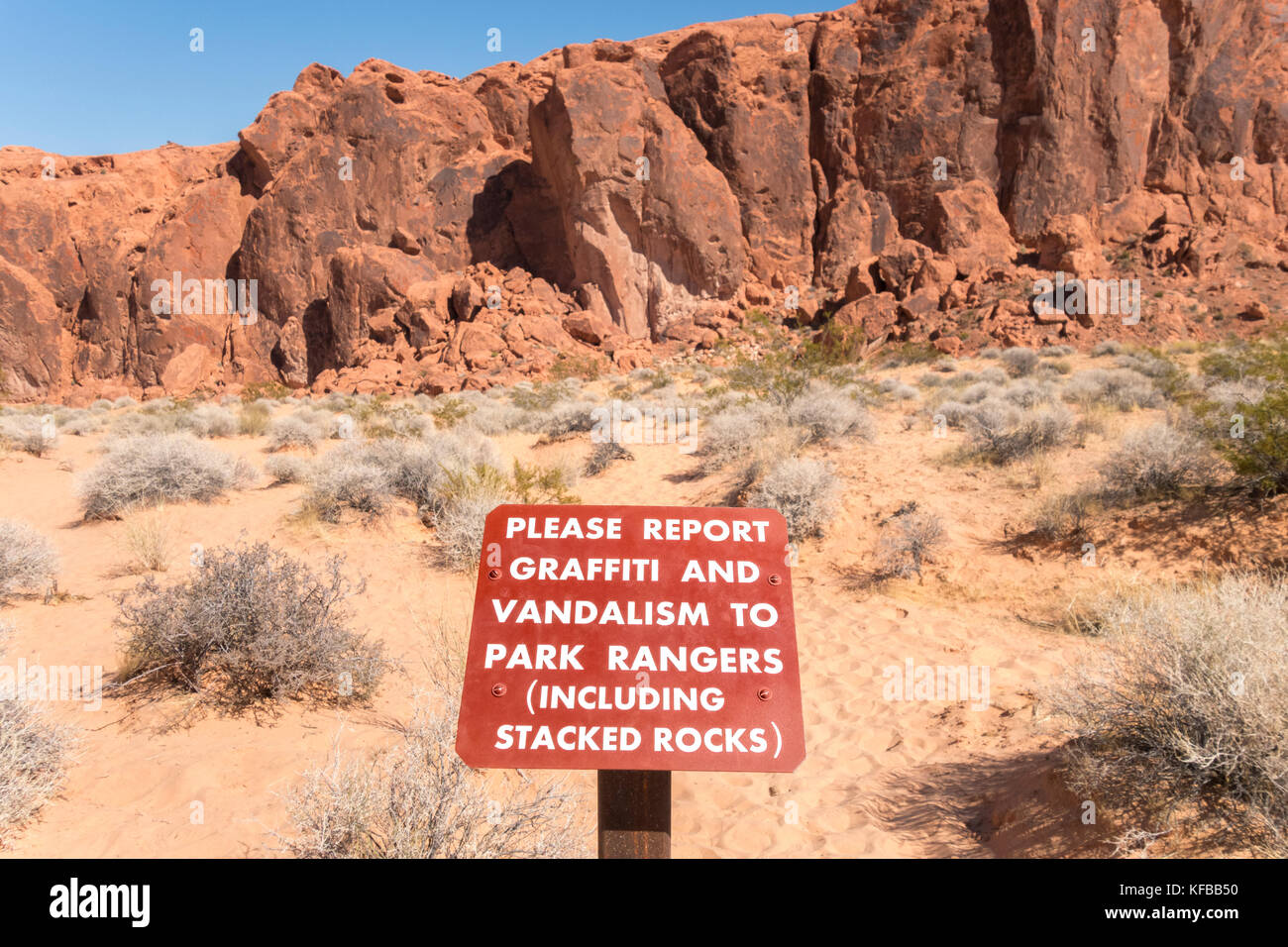 Vallée de Feu Park Nevada, signer avertissement pour signaler un graffiti et vandalisme à des rangers du parc, y compris les roches empilées. Banque D'Images