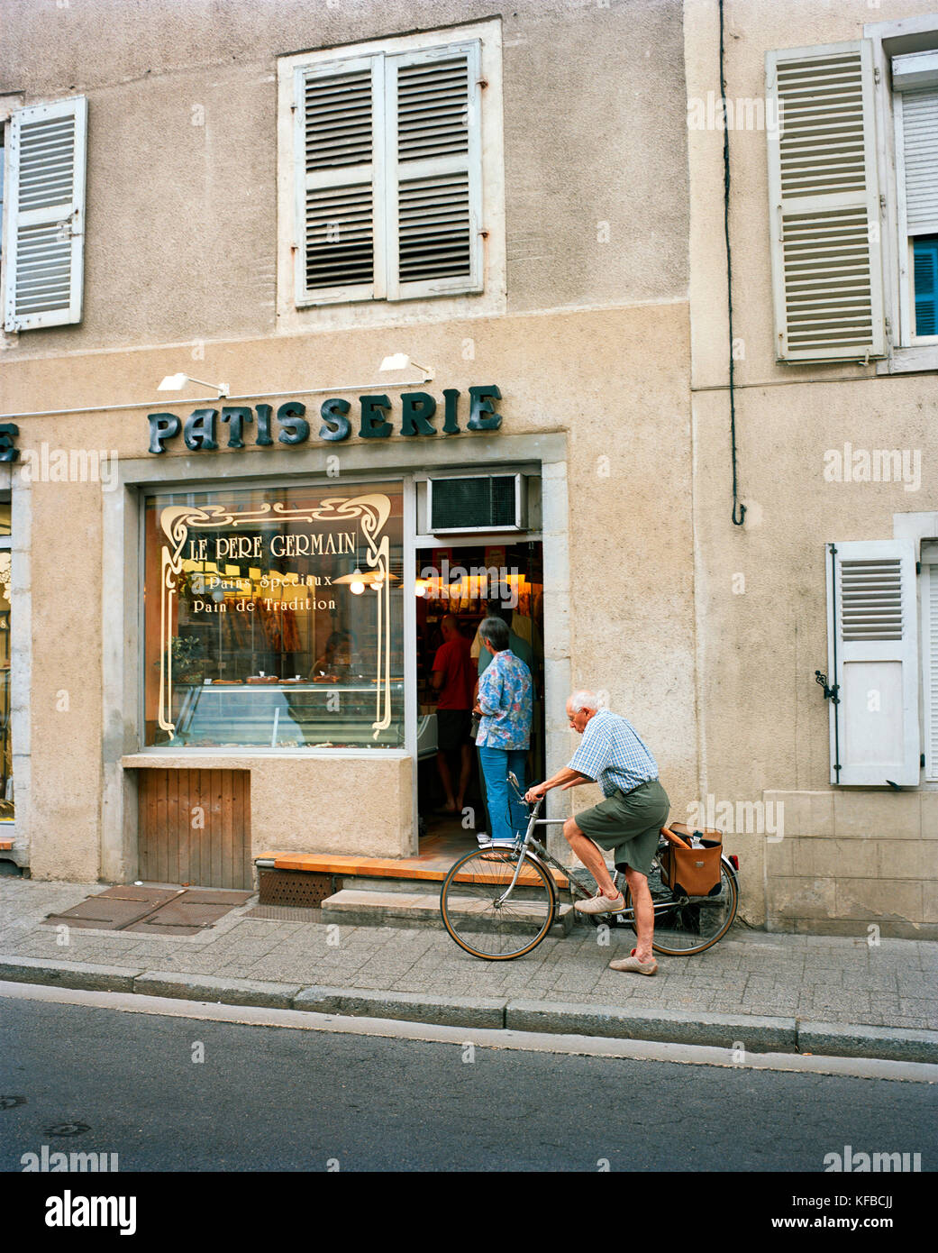 La France, de l'Arbois, l'homme quitte le pere germain patisserie sur son vélo avec du pain dans son panier, région des vins du Jura Banque D'Images