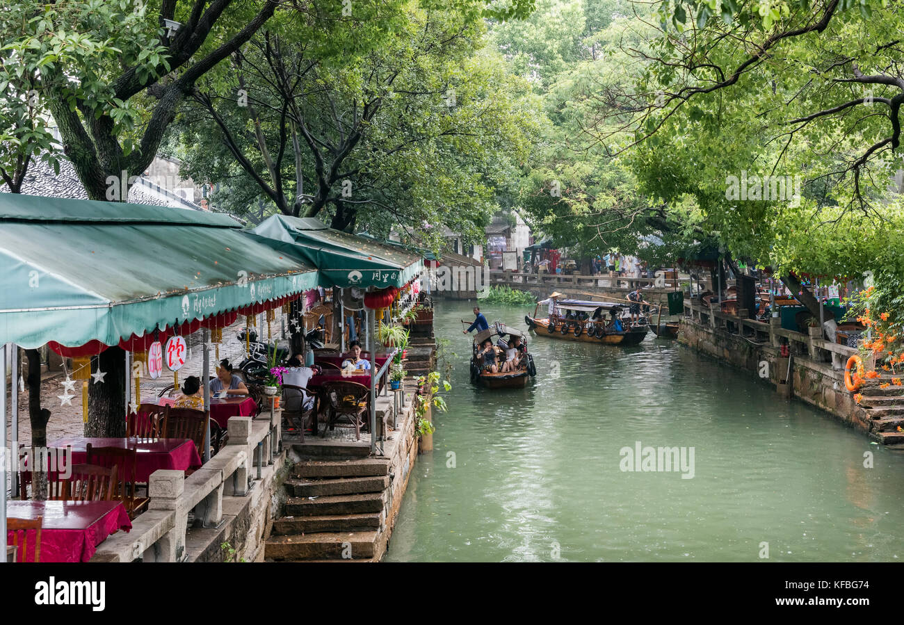 Stock photo - balade en bateaux touristes rangée dans un canal dans une ville ancienne en Chine, une femme est l'une des rames voile aviron est un homme l'autre Banque D'Images