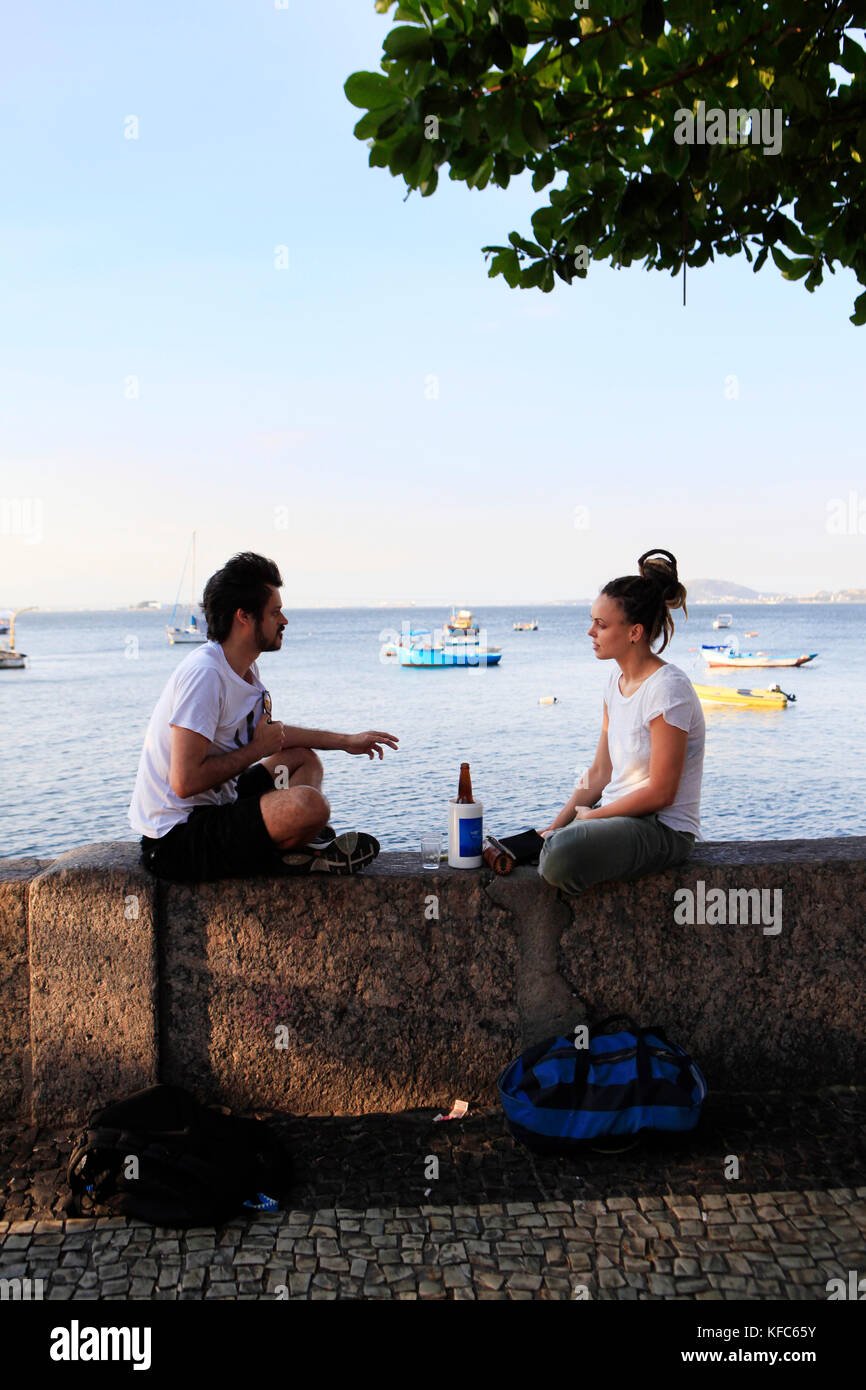 Brésil, Rio de Janeiro, bar urca, les gens s'asseoir sur un mur de la mer sur l'océan Atlantique Banque D'Images