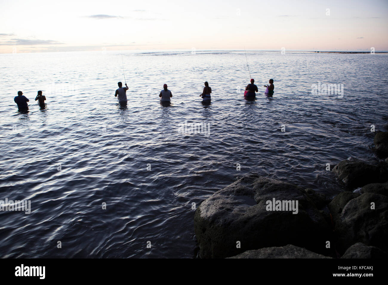 Polynésie française, Tahiti. Plage de sable noir à Tahiti. Les sections locales de la pêche dans l'eau au crépuscule. Banque D'Images