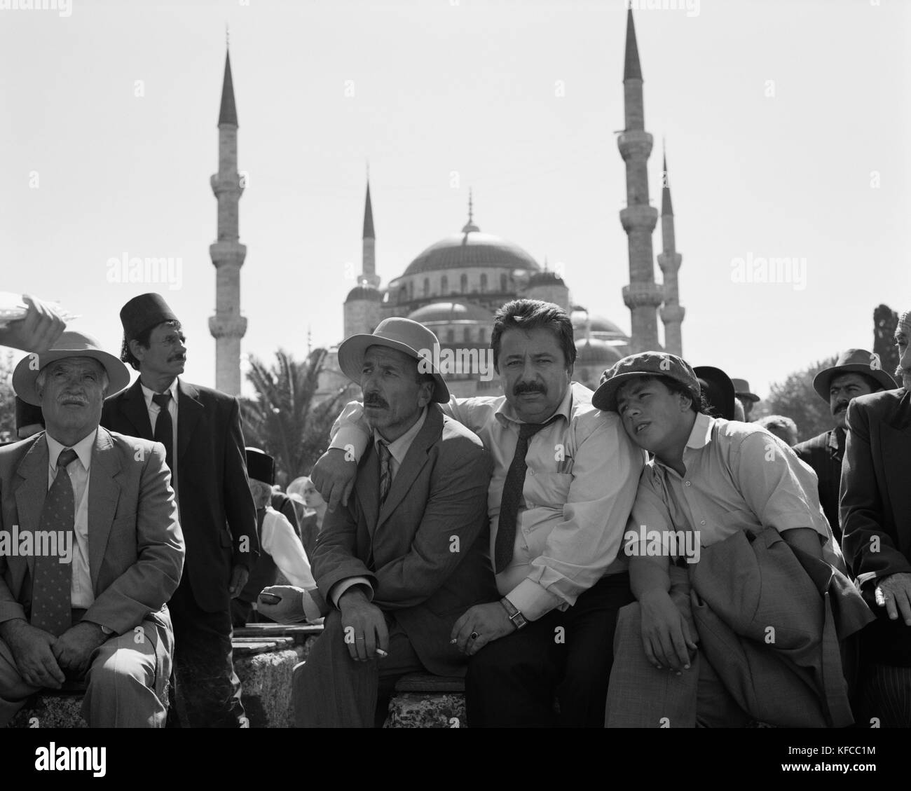 La Turquie, Istanbul, acteurs siégeant ensemble avec mosquée dans l'arrière-plan (B&W) Banque D'Images