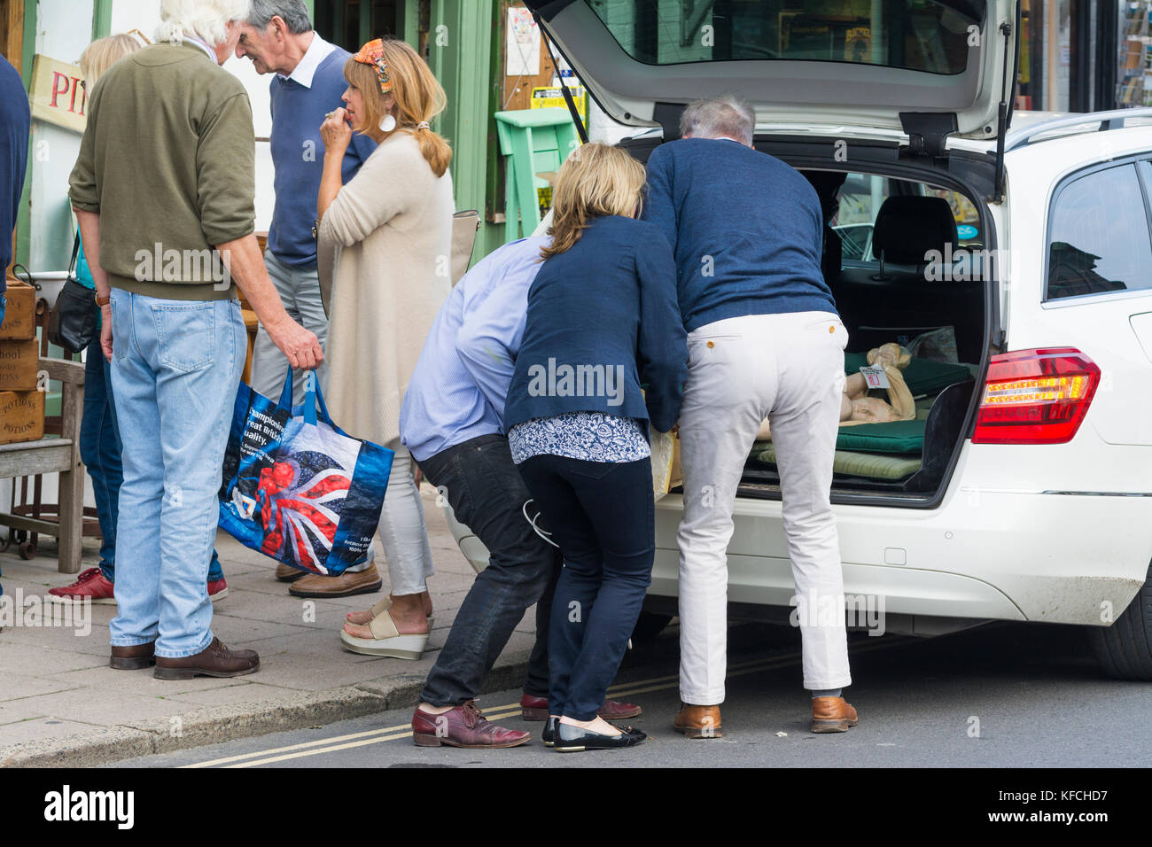 Des gens qui aident à charger une voiture bicorps avec produits après le shopping dans le Royaume-Uni. Banque D'Images