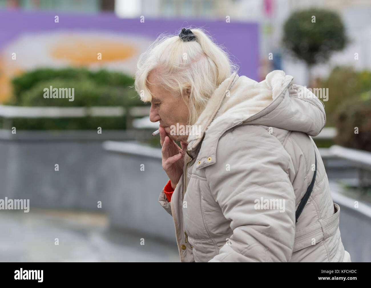 Femme âgée de race blanche fume une cigarette à l'extérieur au Royaume-Uni. Banque D'Images
