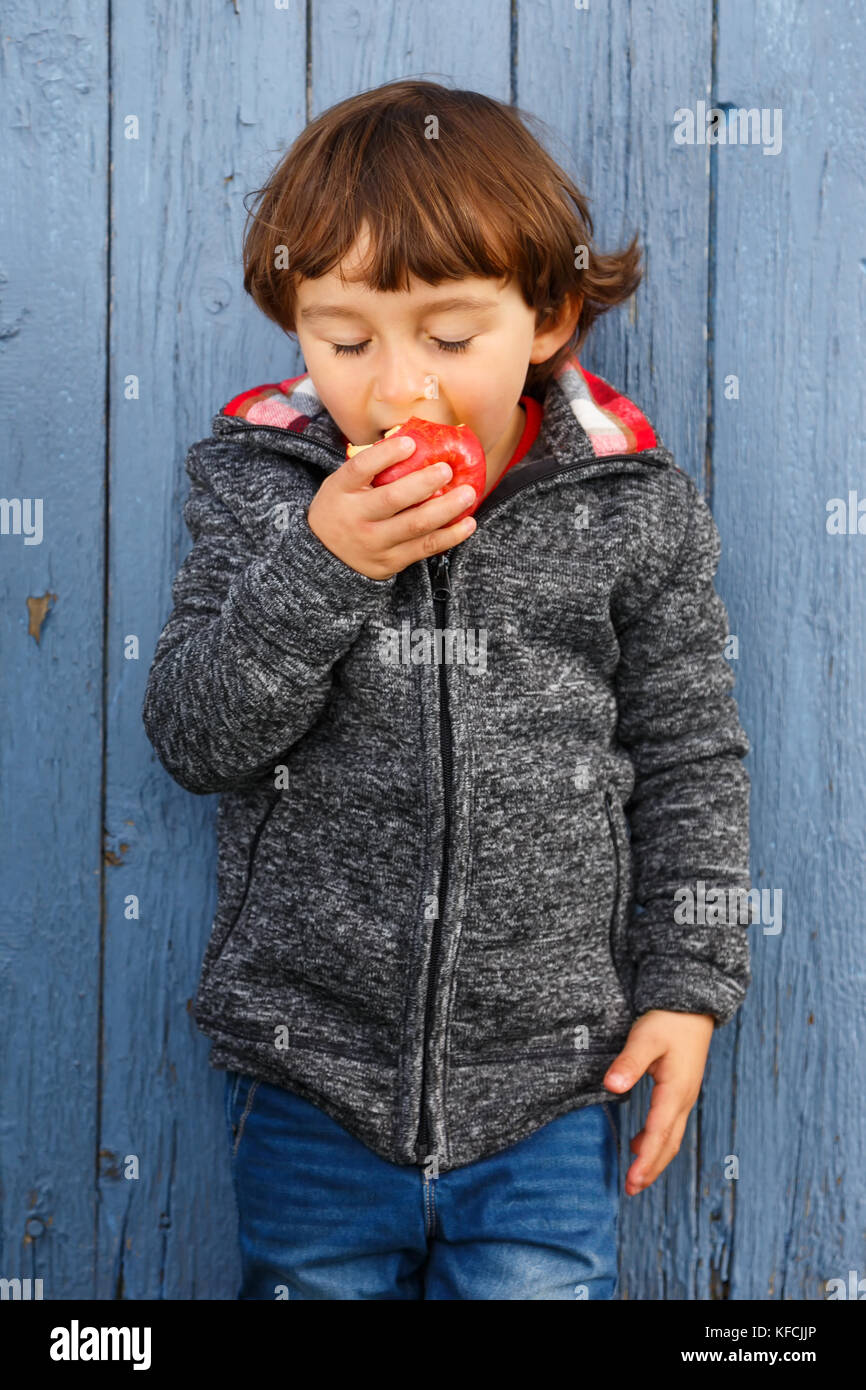 Petit garçon enfant kid manger pomme fruit format portrait automne automne plein air sain Banque D'Images