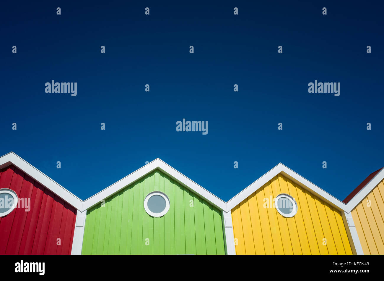 Kavalierspad, Berlin, Allemagne Deutschland. Une vision contemporaine à la recherche jusqu'à une rangée d'affaires locaux locaux qui ont leur devanture commerciale conçu pour ressembler à une rangée de cabines de plage. Chaque vitrine est une couleur différente, ce qui crée beaucoup de contraste avec les formes géométriques sur le ciel bleu profond. Banque D'Images