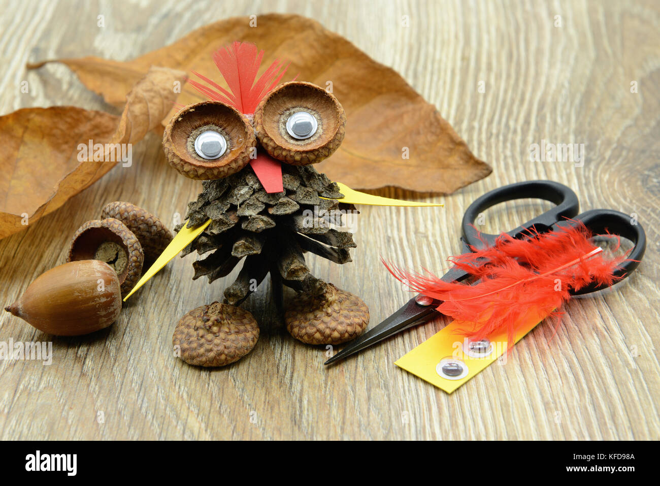 Bricoler un hibou avec cône de pin, acorn et papier avec des plumes. yeux en plastique, papier et scissor de côté. Banque D'Images