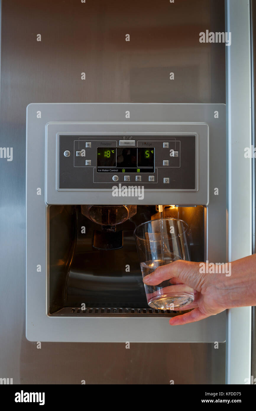 Une main tenant un verre sous le distributeur d'eau d'un frigo américain  libre Photo Stock - Alamy