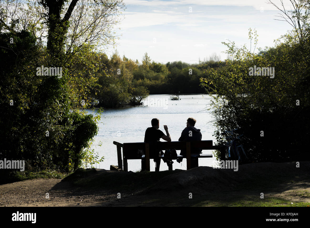 Deux hommes assis près du lac bénéficiant d'automne chaud soleil Banque D'Images