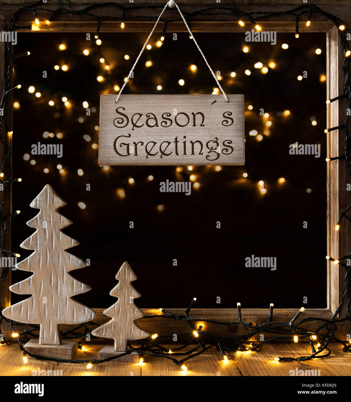 Panneau avec texte anglais seasons greetings. châssis de fenêtre avec des lumières dans la nuit dans l'arrière-plan. Décoration de Noël comme l'arbre de Noël et fairy ligh Banque D'Images