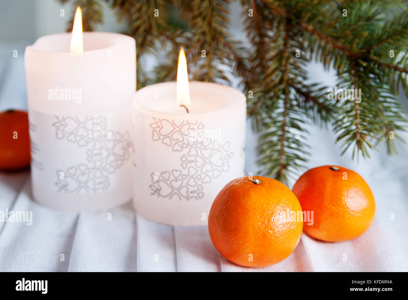 Deux bougies pour fêtes, mandarines et pine brunch sur une nappe blanche Banque D'Images