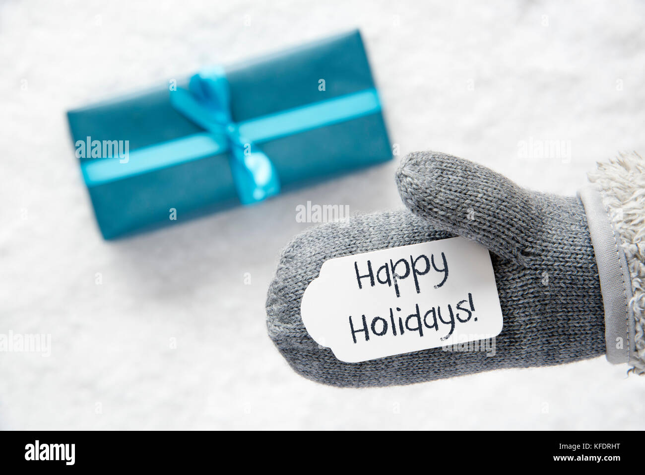 Gant avec étiquette avec le texte anglais de bonnes vacances. turquoise  cadeau ou présent sur neige en arrière-plan. saisonnier carte de vœux Photo  Stock - Alamy