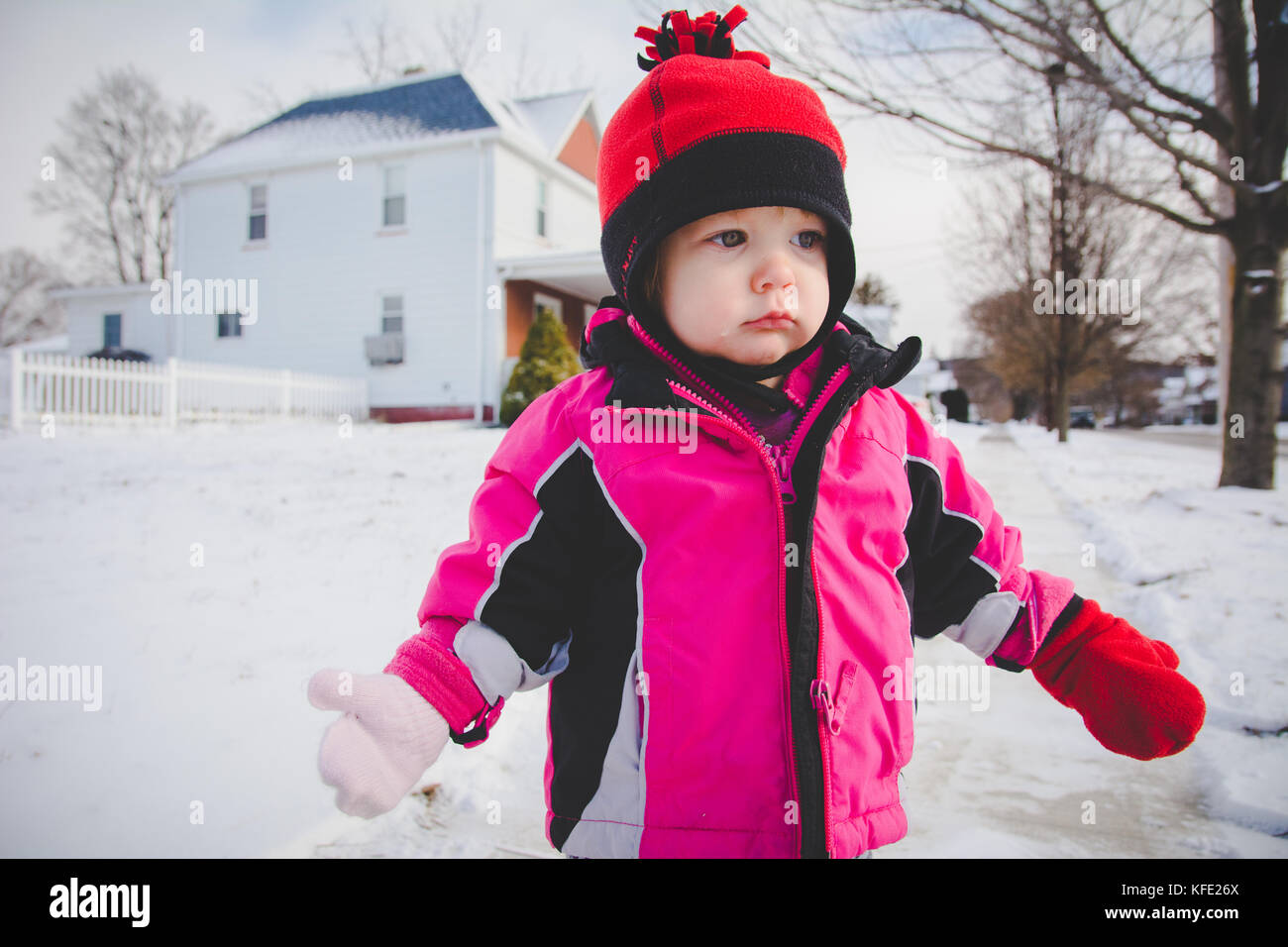 Bébé debout dans la neige portant des vêtements d'hiver Banque D'Images