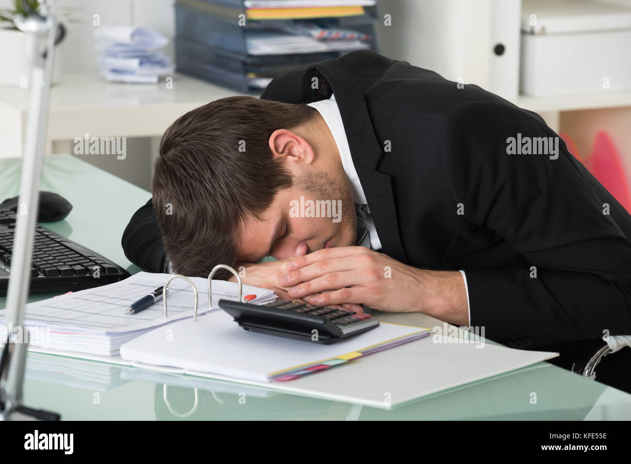 Jeune homme dormir avec les factures sur desk in office Banque D'Images