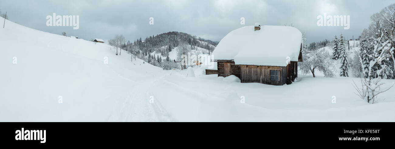 Maison rustique en bois dans des congères sur les pistes en hiver Carpates ukrainiennes par temps nuageux. trois coups de croix panoram haute résolution Banque D'Images