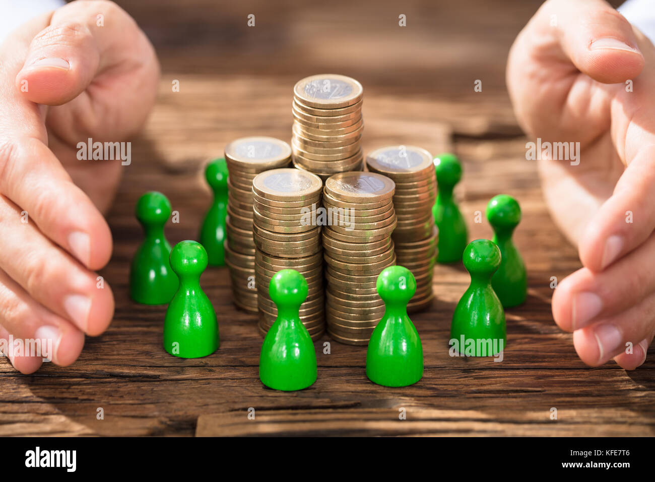 Close-up de mains la protection de la pile pile bouton entouré de figures sur un bureau en bois Banque D'Images