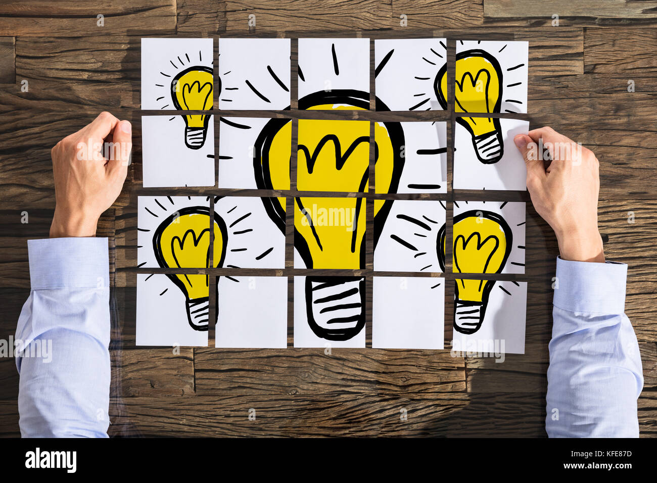 Businessman with Light bulb dimensions sur du papier blanc sur le bureau en bois Banque D'Images