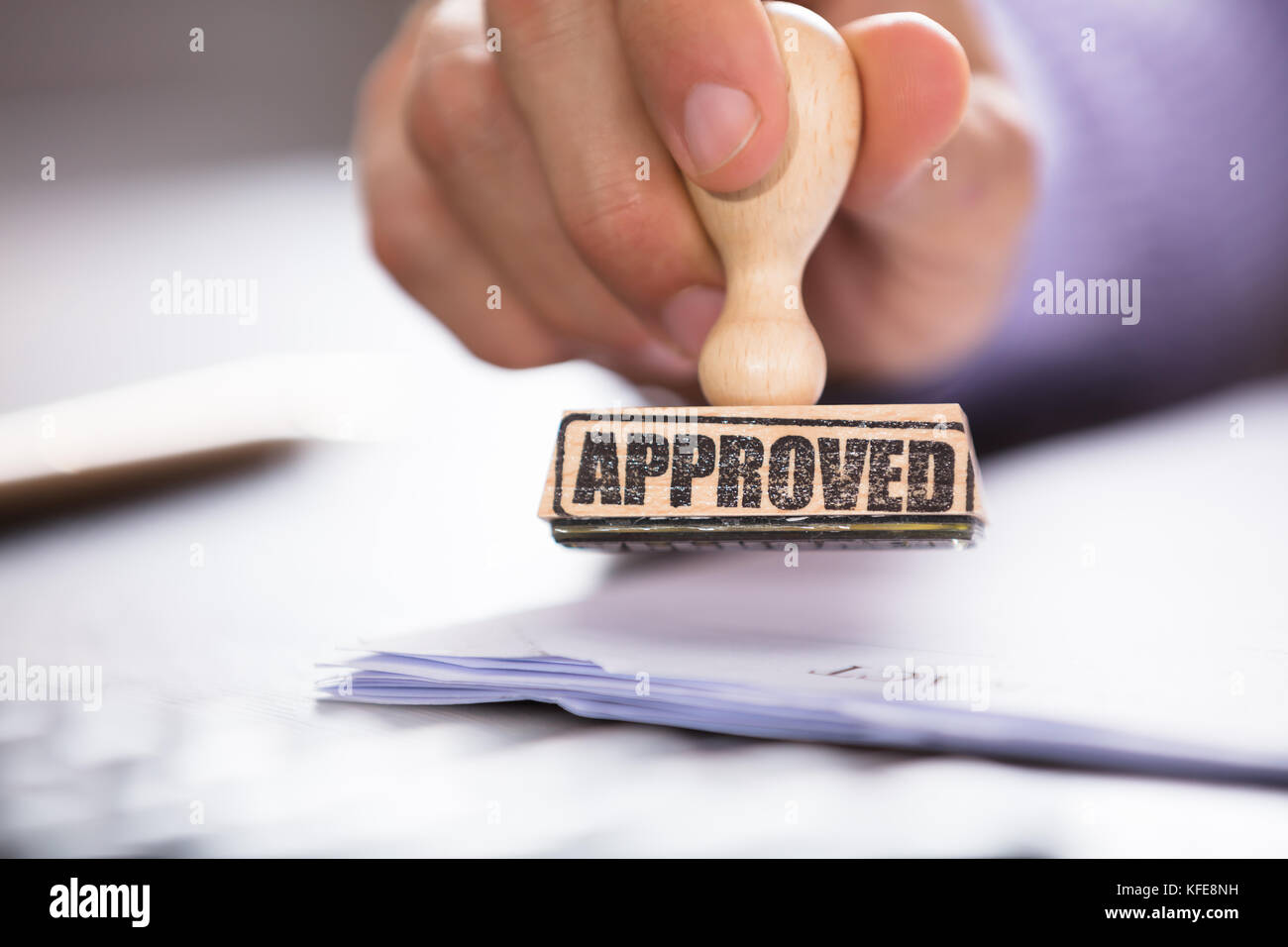 Close-up of a hand holding a approuvé le document sur l'horodateur sur desk in office Banque D'Images