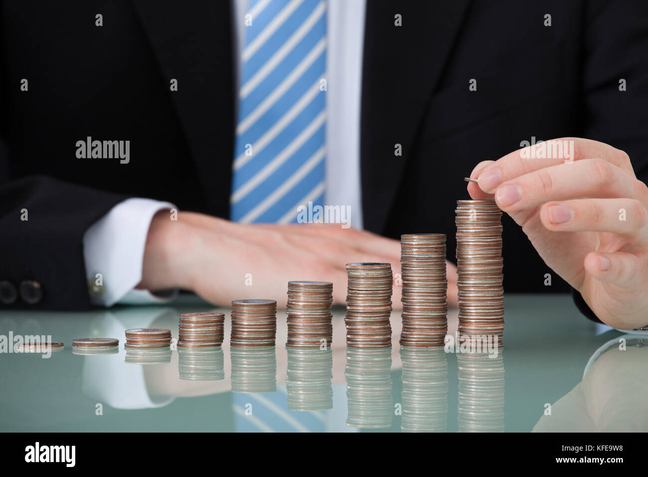 Portrait of young businessman with coins empilés comme graphique à barres table office Banque D'Images