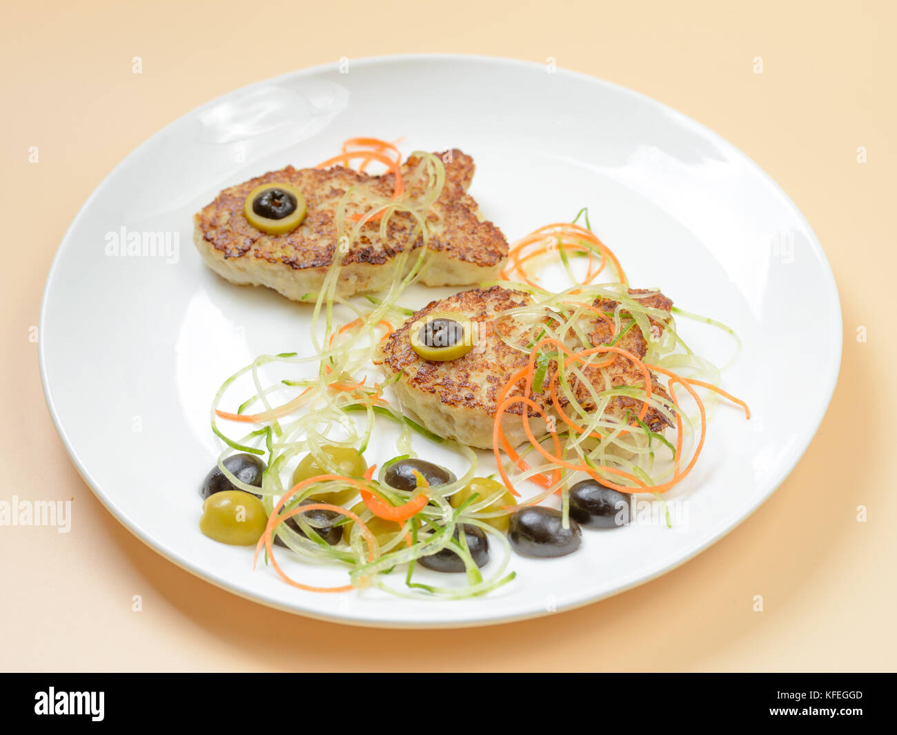 Escalopes de poisson rigolo sur plaque blanche décorée avec des olives et salade Banque D'Images